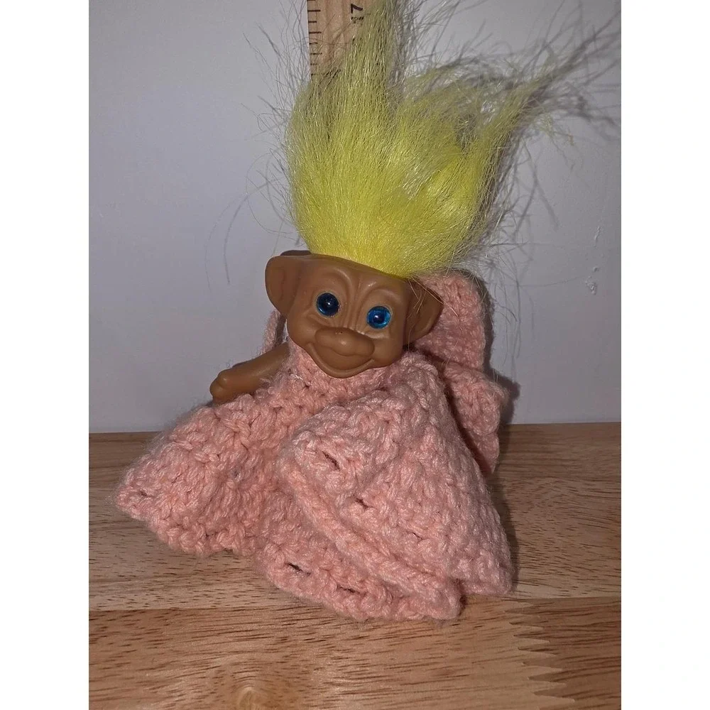 vintage plastic troll doll with bright yellow hair and blue eyes, wearing a hand